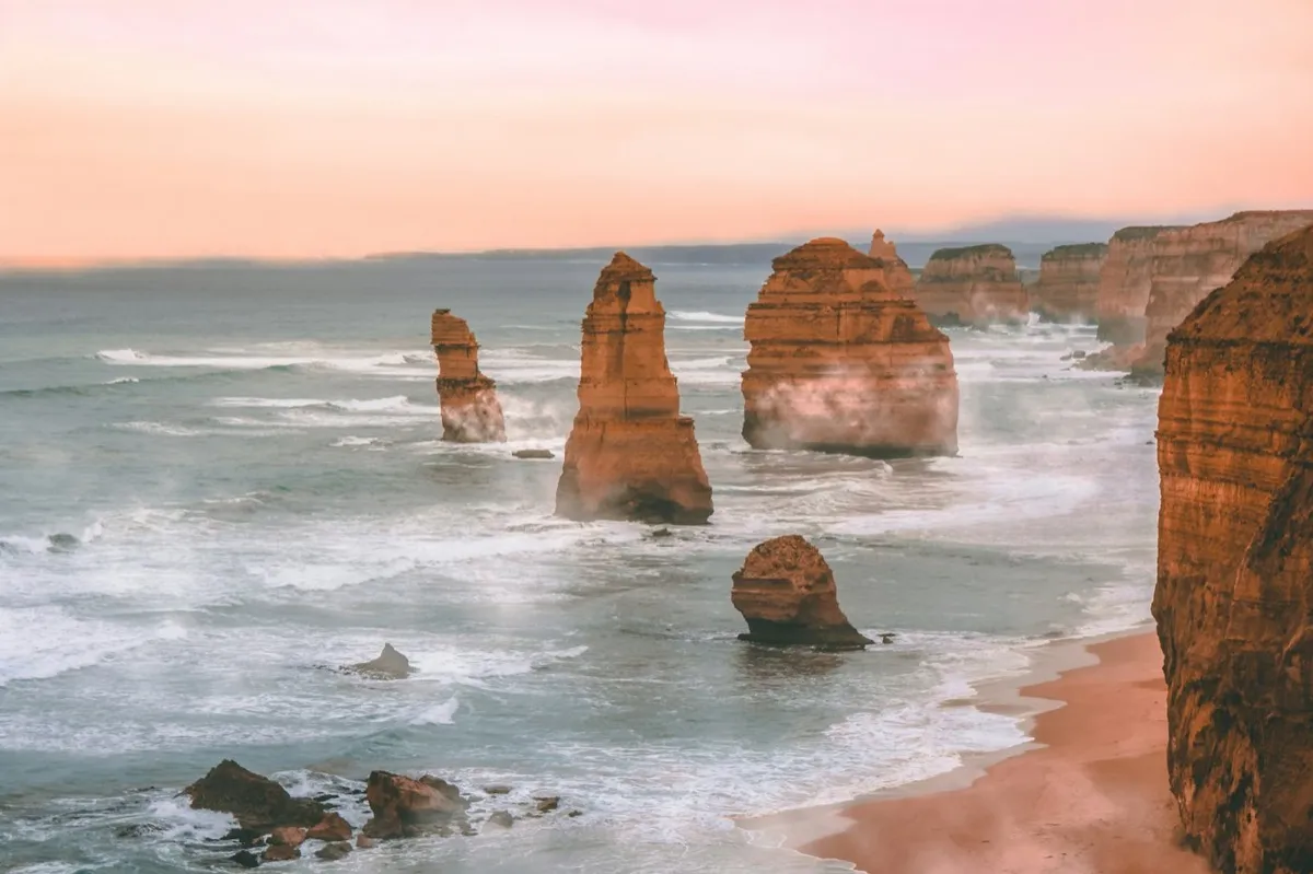 Limestone stacks standing in the surf off a cliffed coast at dusk